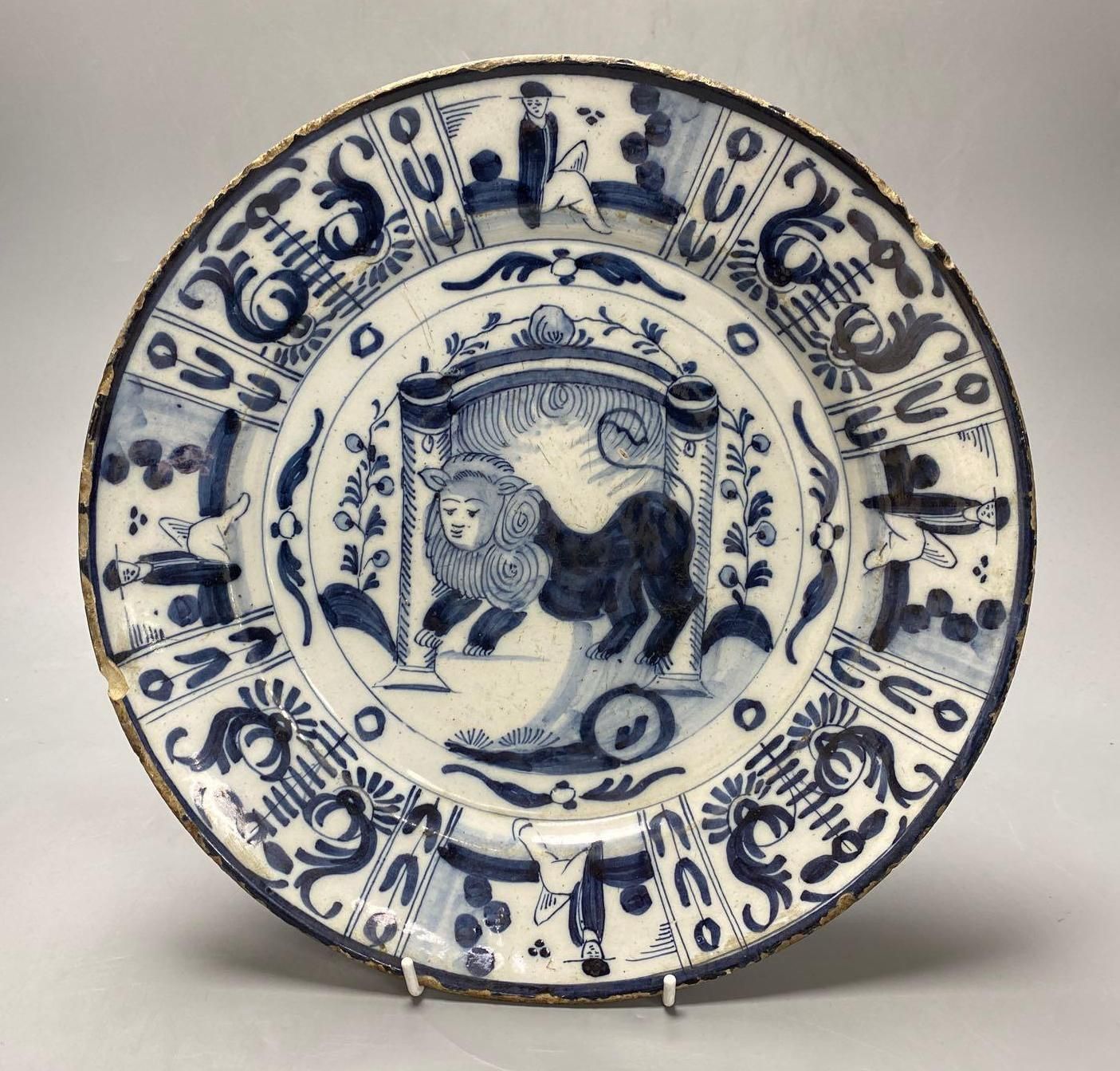 An 18th century Delft blue and white charger centred by a lion, with figural and foliate border, 32cm